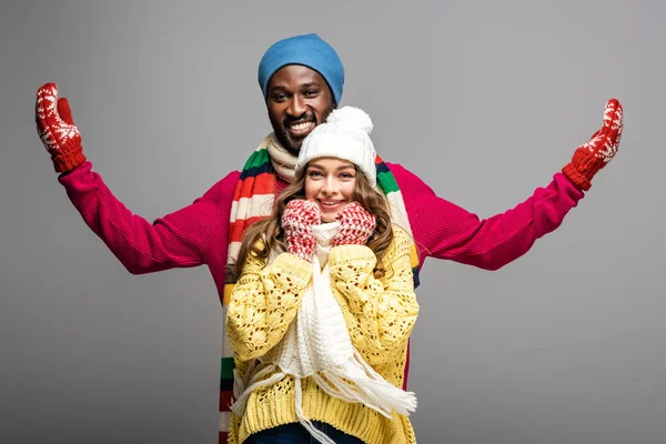 Feliz pareja interracial en invierno traje en gris fondo - foto de stock