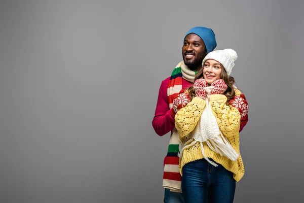 Feliz pareja interracial en invierno traje abrazando en gris fondo - foto de stock