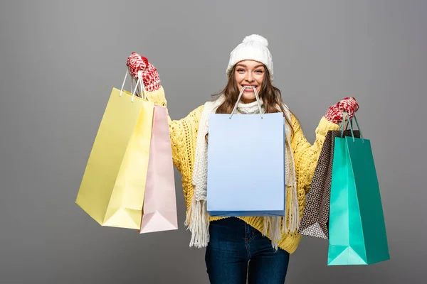 Happy woman in winter outfit with shopping bags on grey background — Stock Photo