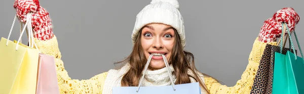 Mujer sorprendida en traje de invierno con bolsas de compras aisladas en gris, tiro panorámico - foto de stock