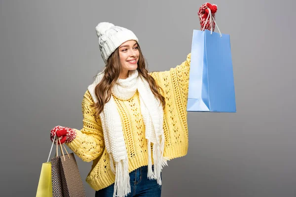 Mujer feliz en traje de invierno con bolsas de compras sobre fondo gris - foto de stock