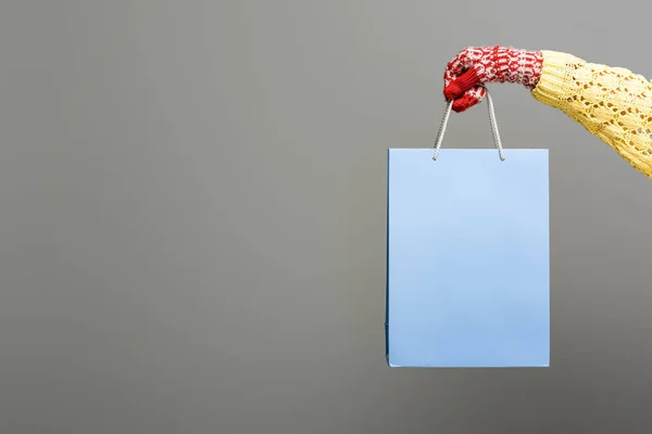 Cropped view of woman in mitten holding shopping bag on grey background — Stock Photo