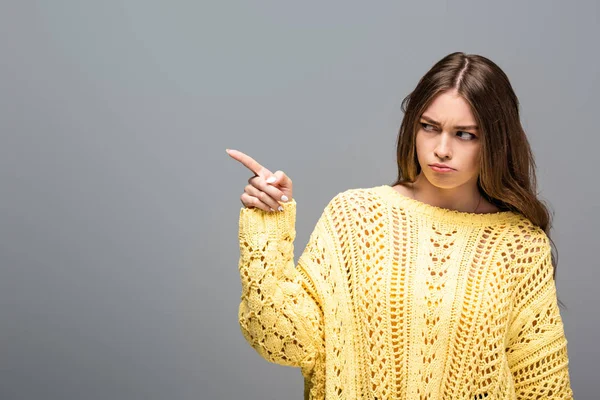 Offended woman in yellow sweater pointing with finger on grey background — Stock Photo