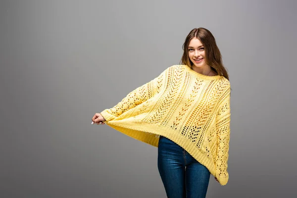 Happy woman holding yellow sweater on grey background — Stock Photo