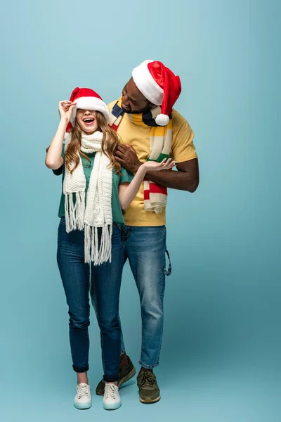 Felice coppia interrazziale in cappelli di Babbo Natale e sciarpe divertirsi — Foto stock