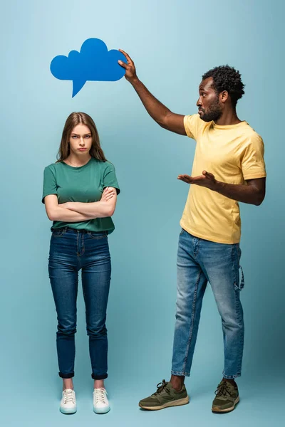 African american man holding thought bubble above offended girlfriend on blue background — Stock Photo