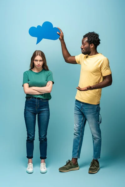Afro-américain homme tenant bulle de pensée ci-dessus offensé petite amie sur fond bleu — Photo de stock