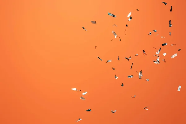 Shiny silver confetti on orange background — Stock Photo