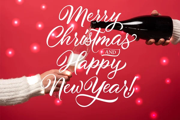 Vue recadrée de l'homme verser du champagne de la bouteille dans des verres sur rouge avec joyeux Noël et bonne année lettrage — Photo de stock