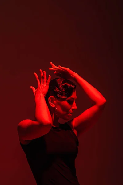 Expressive dancer performing tango on dark background with red lighting — Stock Photo