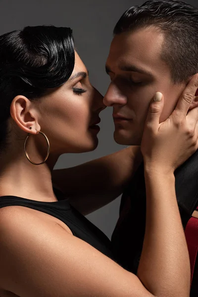 Hermosa bailarina besándose pareja mientras realiza tango aislado en gris - foto de stock