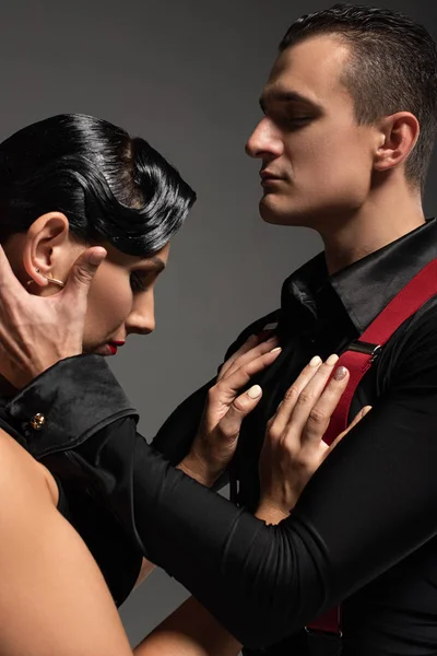 Sensual dancer touching head of beautiful partner while performing tango isolated on grey — Stock Photo