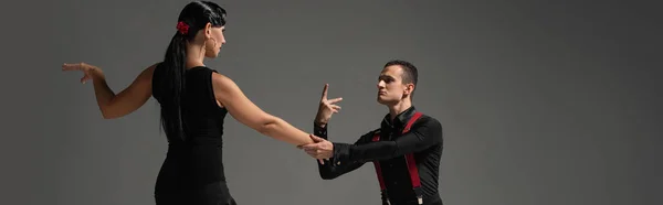 Plano panorámico de pareja expresiva de bailarines realizando tango aislado sobre gris - foto de stock