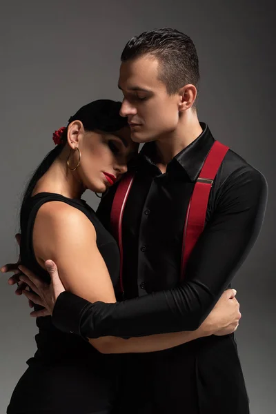 Beau danseur étreignant partnter tout en effectuant tango isolé sur gris — Photo de stock