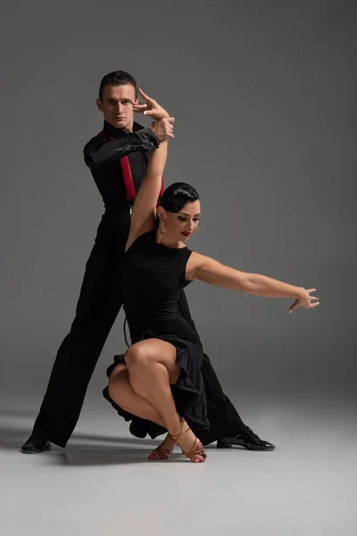 Dançarinos apaixonados em preto, roupas elegantes dançando tango em fundo cinza — Fotografia de Stock