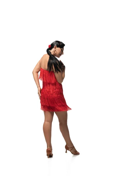 Sensual bailarina en elegante vestido con flecos realizando tango sobre fondo blanco - foto de stock