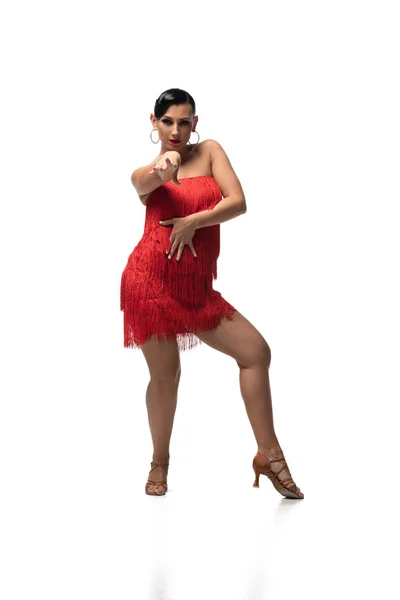 Bailarina expresiva en vestido elegante con flecos mirando a la cámara mientras realiza tango sobre fondo blanco — Stock Photo