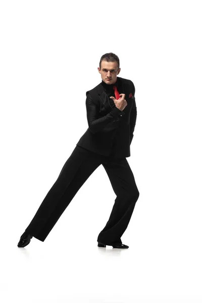Danseur expressif et élégant regardant la caméra tout en exécutant le tango sur fond blanc — Photo de stock