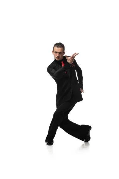 Guapo y elegante bailarín mirando a la cámara mientras realiza tango sobre fondo blanco — Stock Photo