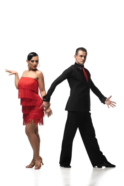 Sinnliche, elegante Tänzerin, die in die Kamera blickt und die Hand ihres attraktiven Partners hält, während sie Tango auf weißem Hintergrund performt — Stockfoto