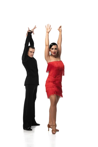 Pareja expresiva de bailarines mirando a la cámara mientras realizan tango con las manos levantadas sobre fondo blanco - foto de stock