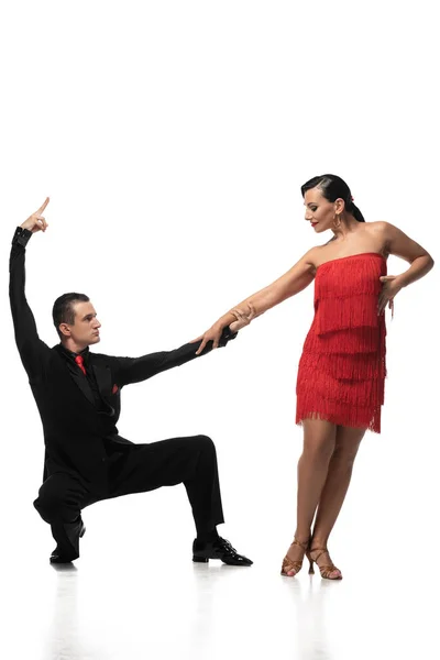 Elegante bailarina en cuclillas y cogida de la mano de atractiva pareja mientras realiza tango sobre fondo blanco - foto de stock