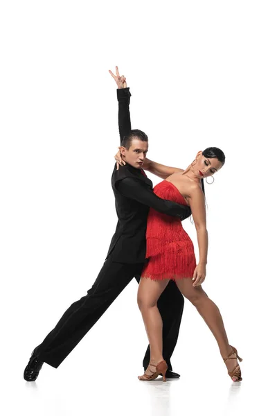 Elegante bailarina mostrando gesto de victoria mientras realiza tango con hermosa pareja sobre fondo blanco - foto de stock