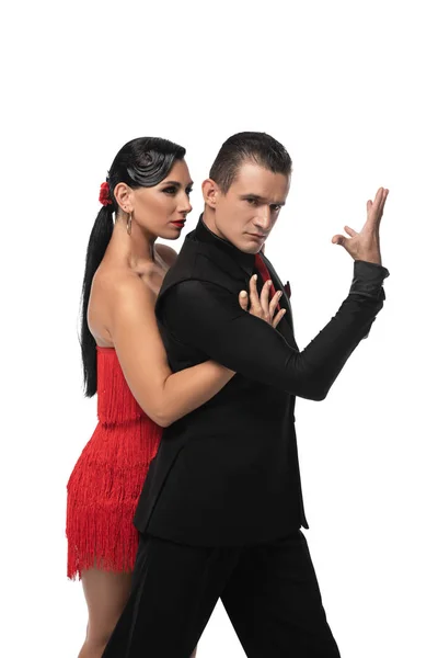 Guapo, elegante bailarín mirando a la cámara mientras realiza tango con hermosa pareja aislada en blanco - foto de stock