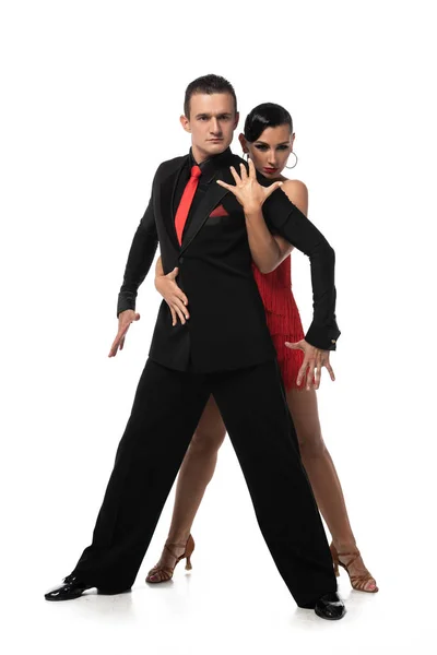 Dançarinos expressivos e elegantes olhando para a câmera enquanto executam tango no fundo branco — Fotografia de Stock