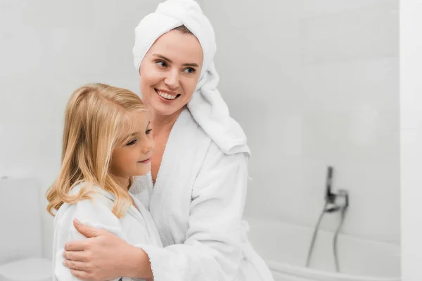 Feliz madre tocando linda hija en cuarto de baño - foto de stock
