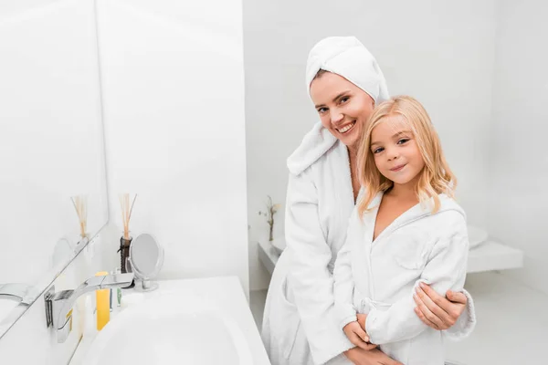 Mujer feliz abrazo linda hija en cuarto de baño - foto de stock