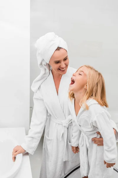 Счастливая мать смотрит на симпатичную дочь в ванной — стоковое фото