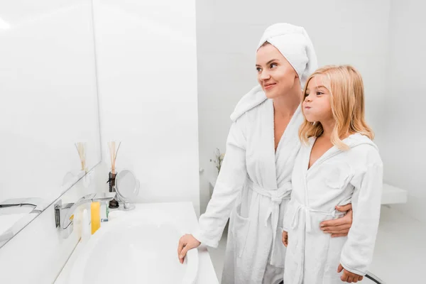 Adorable kid and attractive mother looking at mirror in bathroom — Stock Photo