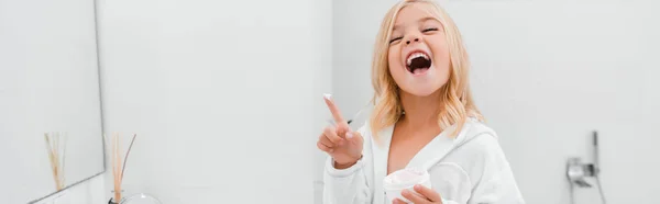 Tiro panorámico de niño feliz con crema cosmética en el dedo riendo en el baño - foto de stock