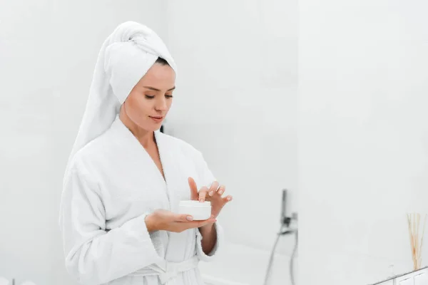 Attraente donna che tiene contenitore con crema viso — Foto stock