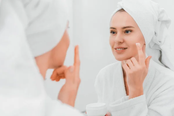 Foco seletivo da mulher aplicando creme cosmético no banheiro — Fotografia de Stock