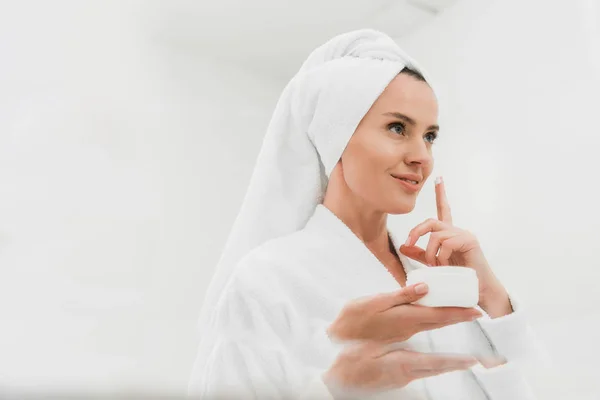 Atractiva mujer aplicando crema cosmética en el baño - foto de stock