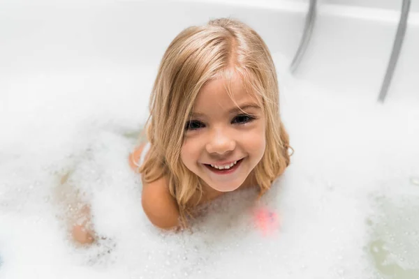 Над головой вид счастливого обнаженного ребенка принимающего ванну — стоковое фото