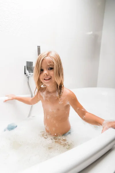 Bambino sorridente e nudo che fa il bagno nella vasca da bagno — Foto stock