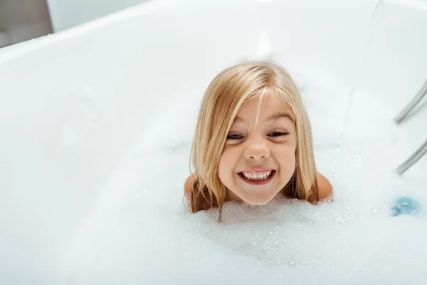 Niño desnudo feliz tomando baño con espuma de baño - foto de stock