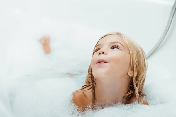 Adorable niño desnudo tomando baño con espuma de baño en casa - foto de stock