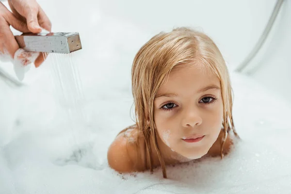 Cute and nude kid taking bath near mother in bathroom — Stock Photo