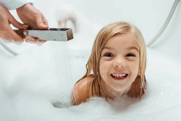 Cute and naked kid taking bath near mother in bathroom — Stock Photo