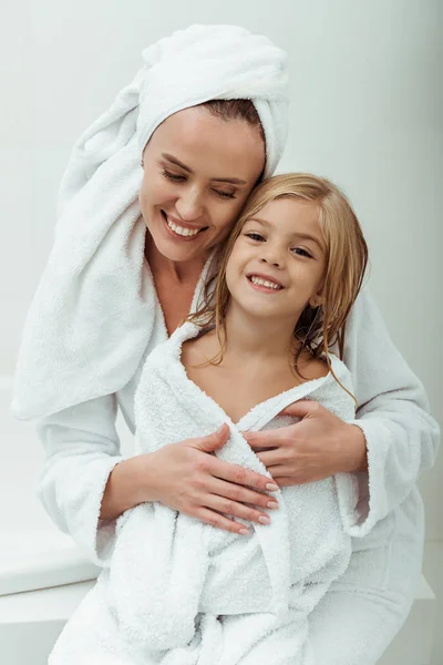 Glückliche Mutter lächelt, während sie Tochter im Badezimmer umarmt — Stockfoto