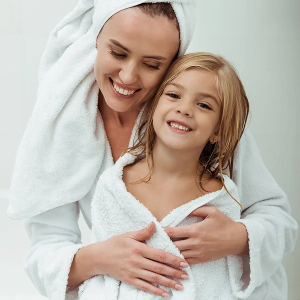 Fröhliche Mutter lächelt, während sie Tochter im Badezimmer umarmt — Stockfoto