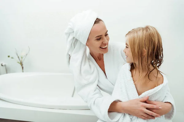 Glückliche Mutter lächelt, während sie ihre Tochter im Badezimmer ansieht — Stockfoto