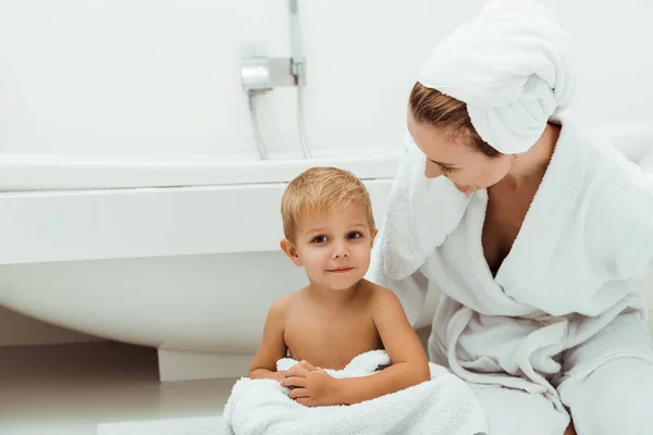 Happy mother smiling while looking at toddler boy in bathroom — Stock Photo