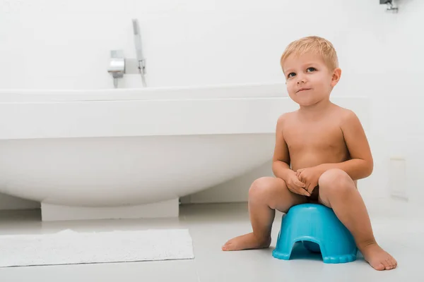 Entzückender Kleinkind Junge sitzt auf blauem Töpfchen in der Nähe der Badewanne — Stockfoto