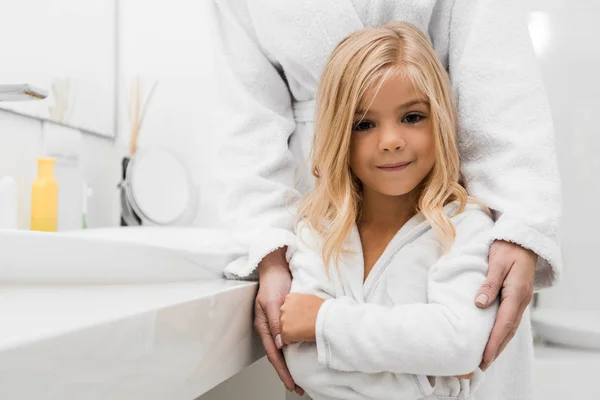 Mignonne fille debout avec mère dans la salle de bain — Photo de stock