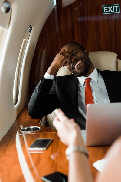 Selective focus of african american businessman laughing near businesswoman in private plane — Stock Photo